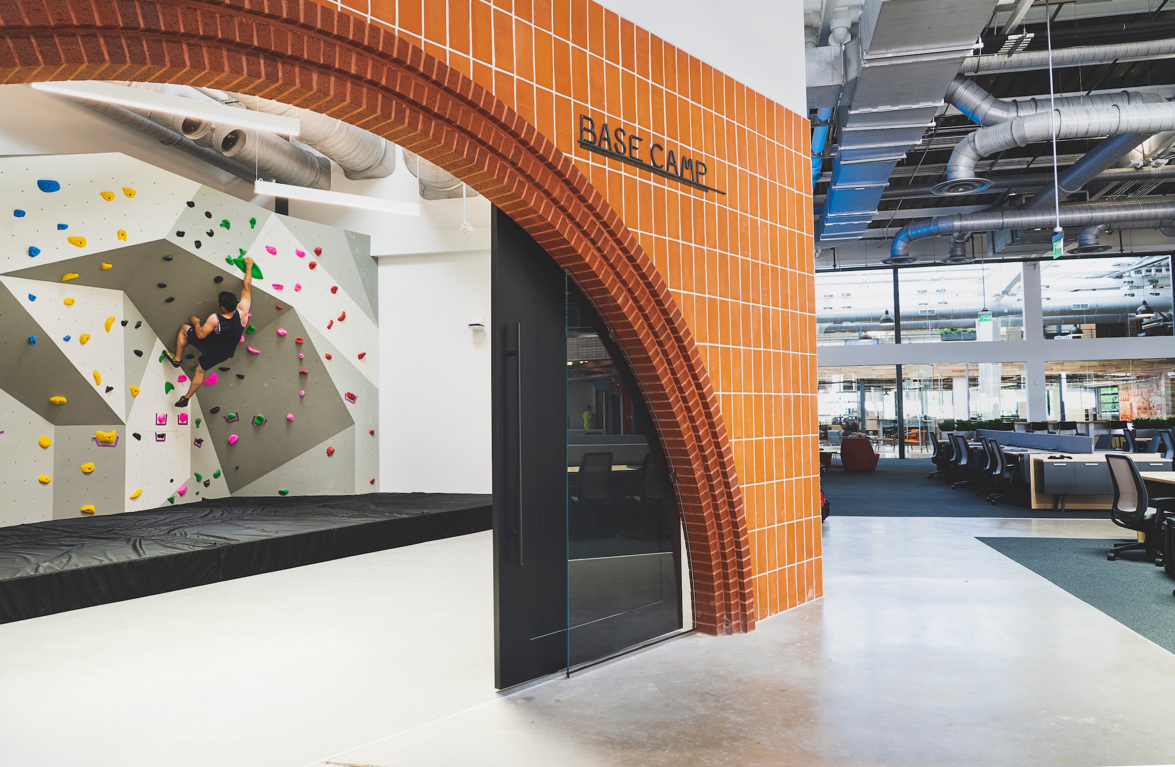 Man sport climbs on a bouldering wall in an office building
